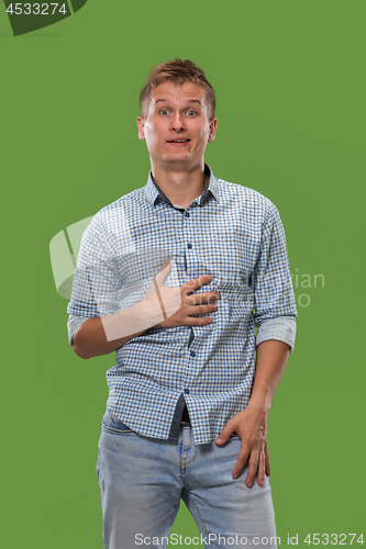 Image of The young attractive man looking suprised isolated on green