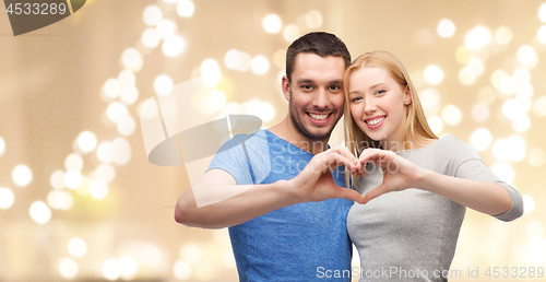 Image of couple showing hand heart over festive lights