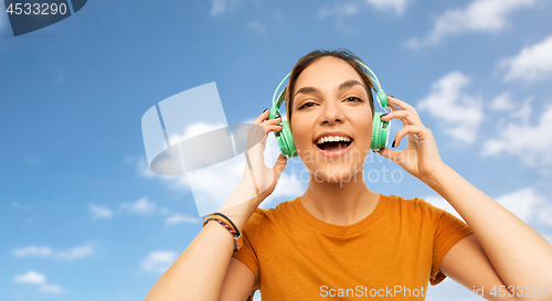 Image of teenage girl in earphones over sky