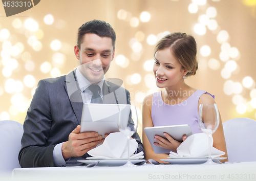 Image of couple with menu on tablet computers at restaurant