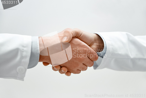 Image of close up of two male doctors shaking hands