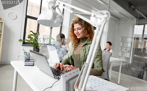 Image of creative woman with laptop working at office