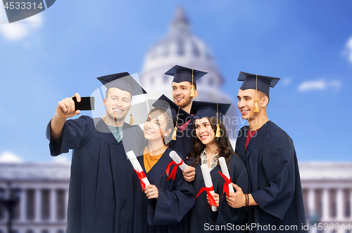 Image of graduates with diplomas taking selfie by cellphone