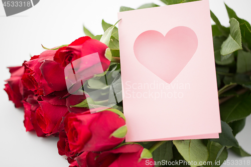 Image of close up of red roses and greeting card with heart