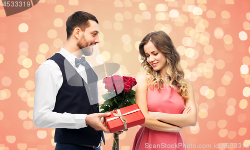 Image of happy man giving woman flowers and present