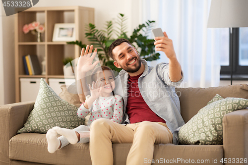 Image of father and daughter taking selfie at home