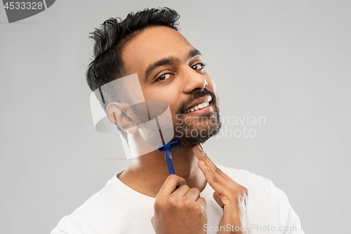 Image of indian man shaving beard with razor blade