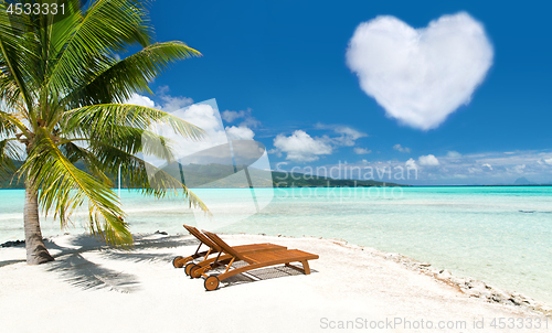 Image of beach with two sunbeds and heart shaped cloud