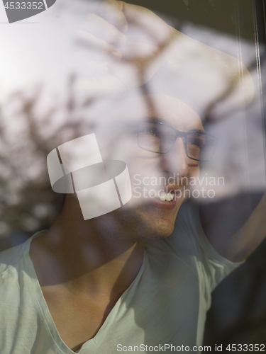 Image of young man drinking morning coffee by the window