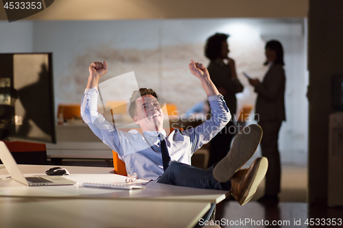 Image of businessman sitting with legs on desk at office