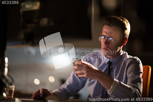 Image of man using mobile phone in dark office