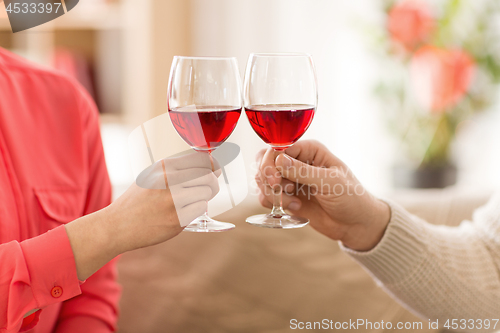 Image of hands of couple with red wine glasses toasting 