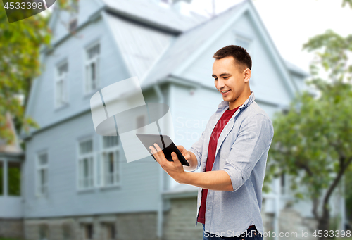 Image of happy young man with tablet computer over house