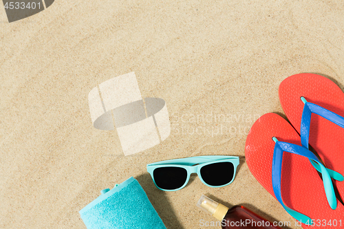 Image of straw hat, flip flops and sunglasses on beach sand