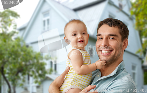 Image of happy father holding baby daughter over house