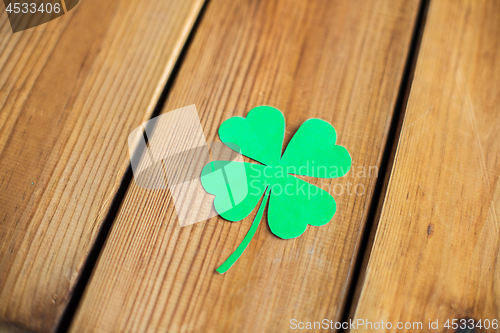 Image of green paper four-leaf clover on wooden background