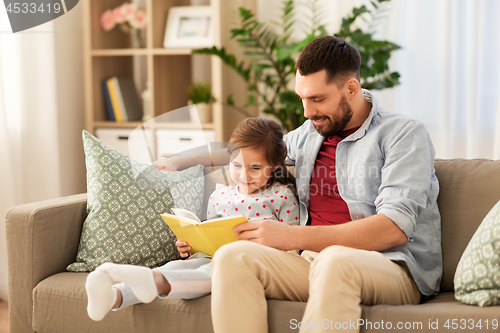 Image of happy father and daughter reading book at home