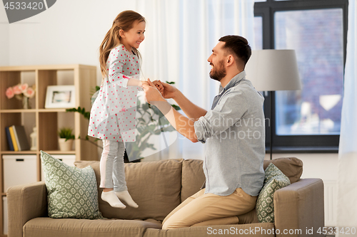 Image of father and daughter jumping and having fun at home