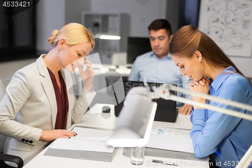 Image of business team with laptop working late at office