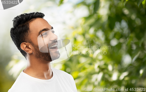 Image of young laughing indian man over natural background