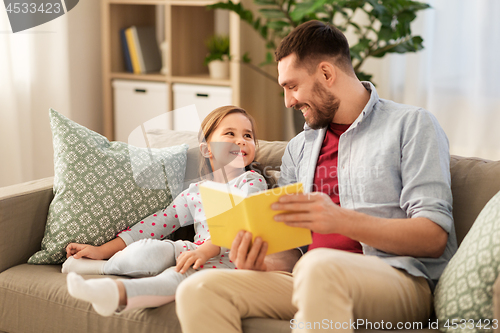 Image of happy father and daughter reading book at home