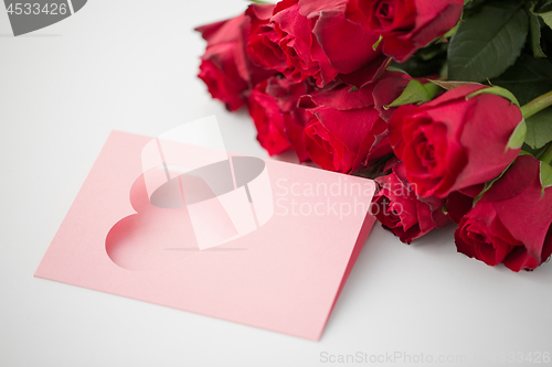 Image of close up of red roses and greeting card with heart