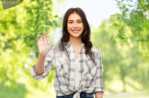 Image of teenage girl showing ok over natural background