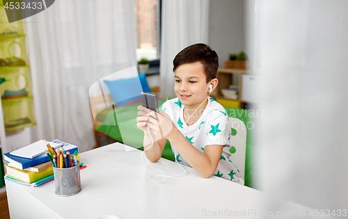 Image of boy in earphones listening to music on smartphone