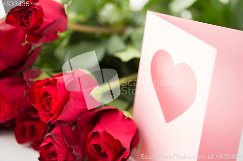 Image of close up of red roses and greeting card with heart