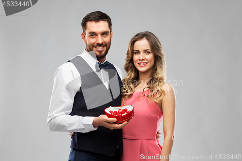 Image of happy couple with chocolate box in shape of heart