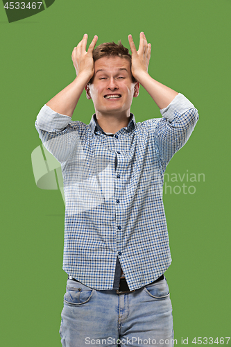 Image of Man having headache. Isolated over green background.