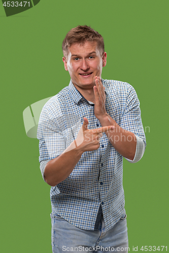 Image of The young man whispering a secret behind her hand over green background