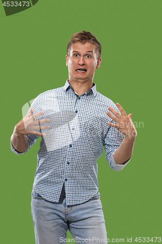 Image of The young attractive man looking suprised isolated on green
