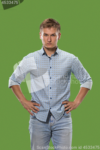 Image of The serious businessman standing and looking at camera against green background.