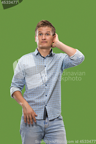 Image of Let me think. Doubtful pensive man with thoughtful expression making choice against green background