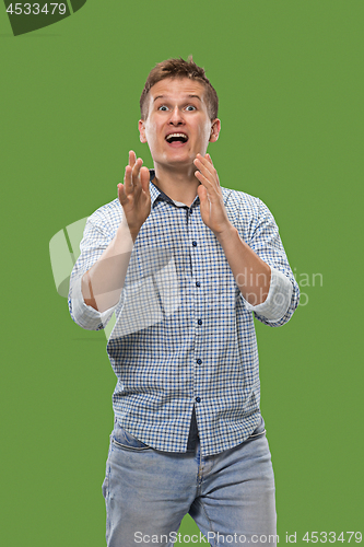 Image of The young attractive man looking suprised isolated on green