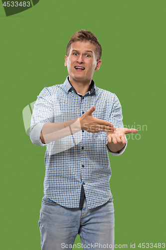 Image of Beautiful male half-length portrait isolated on green studio backgroud. The young emotional surprised man