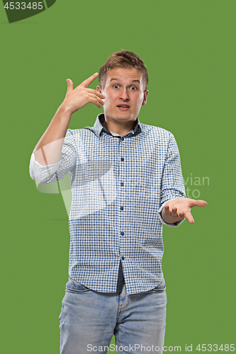 Image of Beautiful male half-length portrait isolated on green studio backgroud. The young emotional surprised man