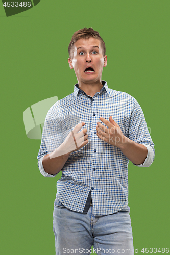 Image of The young attractive man looking suprised isolated on green