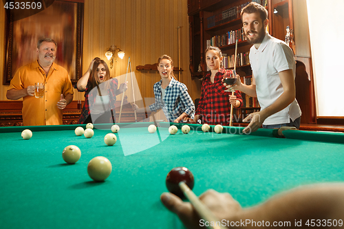 Image of Young men and women playing billiards at office after work.