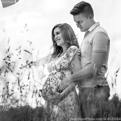 Image of Young happy pregnant couple hugging in nature.