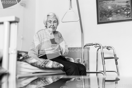 Image of Elderly 96 years old woman operating TV or DVD with remote control