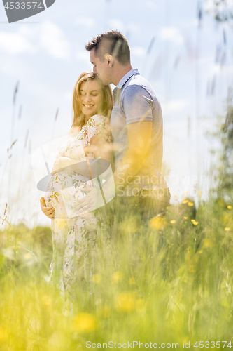 Image of Young happy pregnant couple hugging in nature.