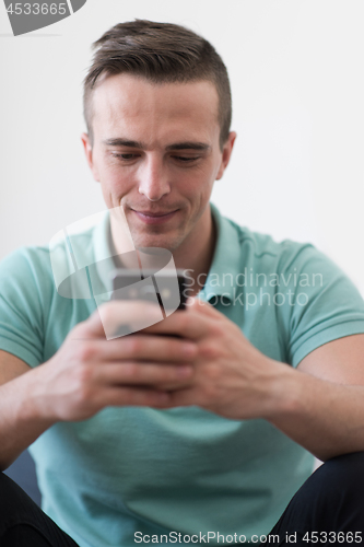 Image of young man using a mobile phone  at home