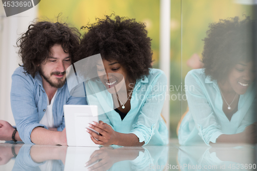 Image of Couple relaxing together at home with tablet computer