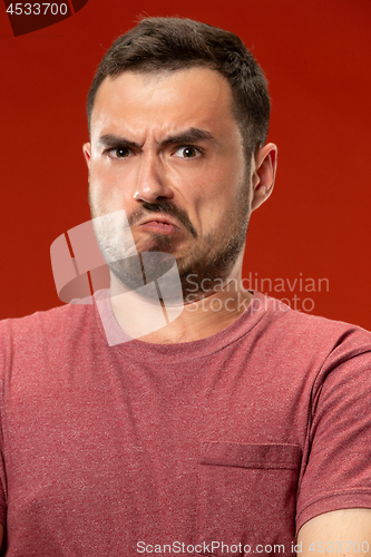 Image of The young emotional angry man screaming on red studio background