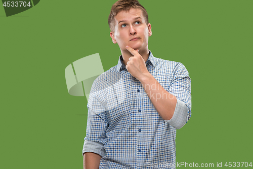 Image of Let me think. Doubtful pensive man with thoughtful expression making choice against green background