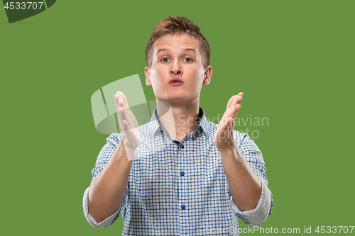 Image of Beautiful male half-length portrait isolated on green studio backgroud. The young emotional surprised man