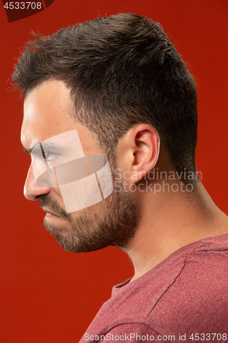 Image of The young emotional angry man screaming on red studio background