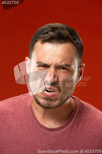 Image of The young emotional angry man screaming on red studio background